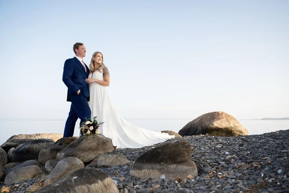 Wedding couple posing for photos on rocky shore at Shore Acres. 