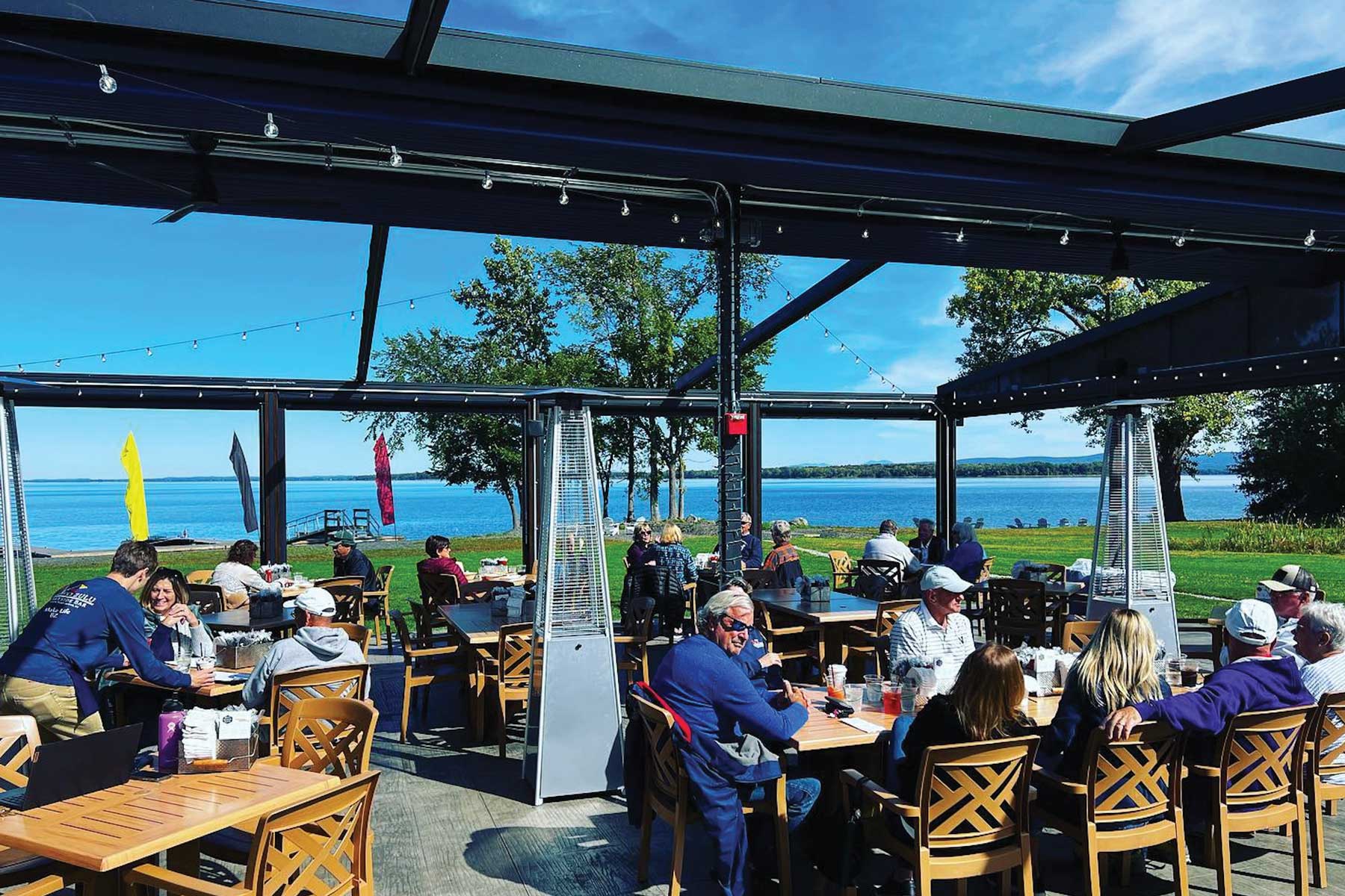 Bravo Zulu Lakeside Bar on a sunny day with the retractable roof open, and a view of Lake Champlain.