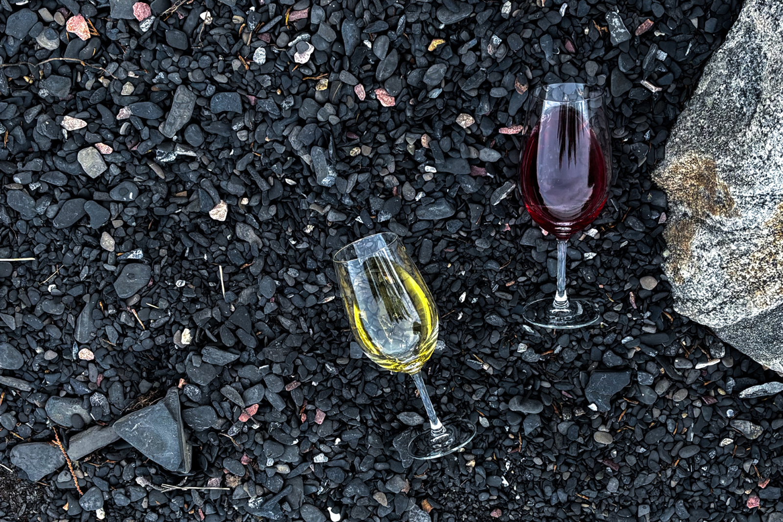 An image of wine glasses against dark rocks.